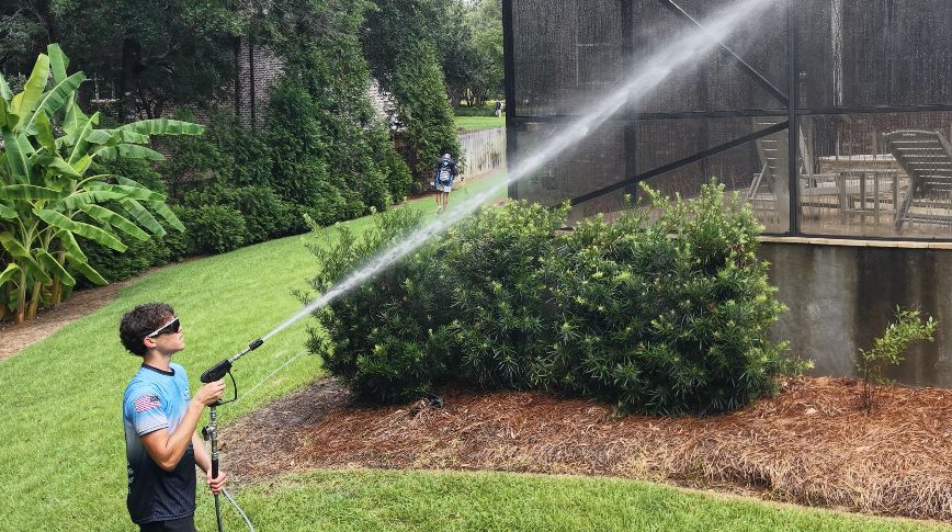 Wave Force technician soft washing a screened pool enclosure