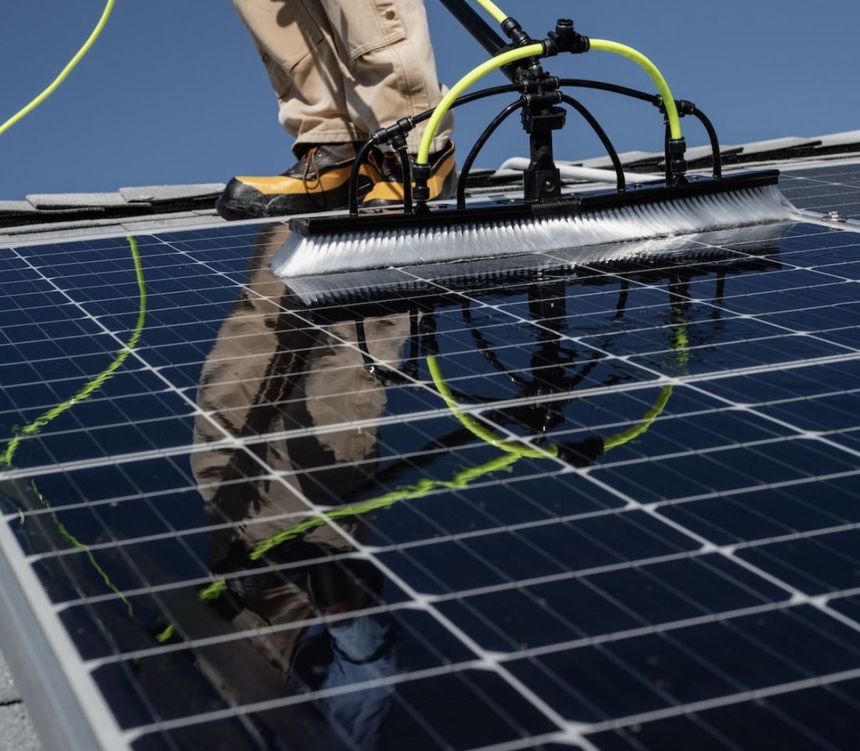 Water-fed brush cleaning a rooftop solar panel array with purified water